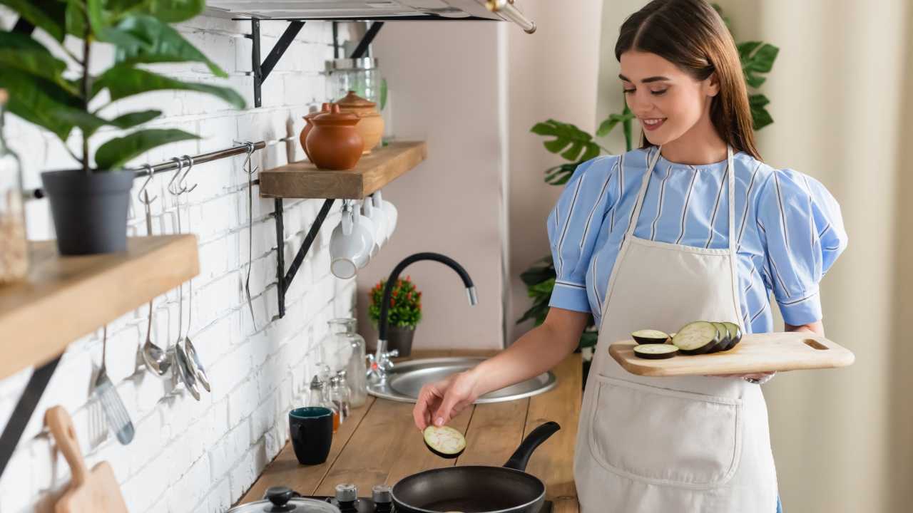 Giovane donna prepara le melanzane in padella - foto Depositphotos - Solofinanza.it