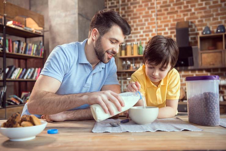 Papà e figlio fanno insieme colazione con del latte e cereali - foto Depositphotos - Solofinanza.it